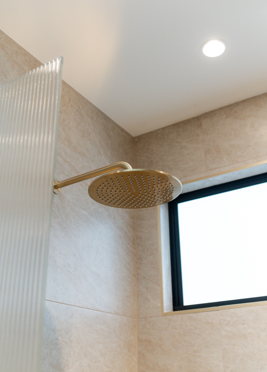 Brass shower head in a tiled bathroom